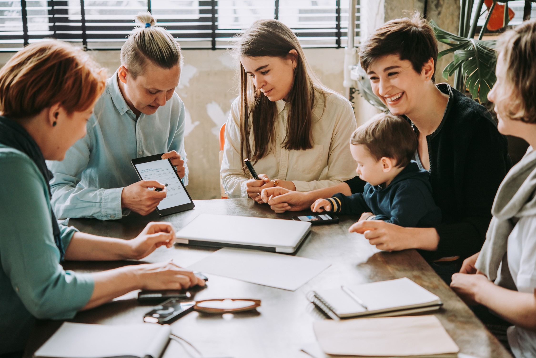 Business meeting with professionals reviewing documents and small child present