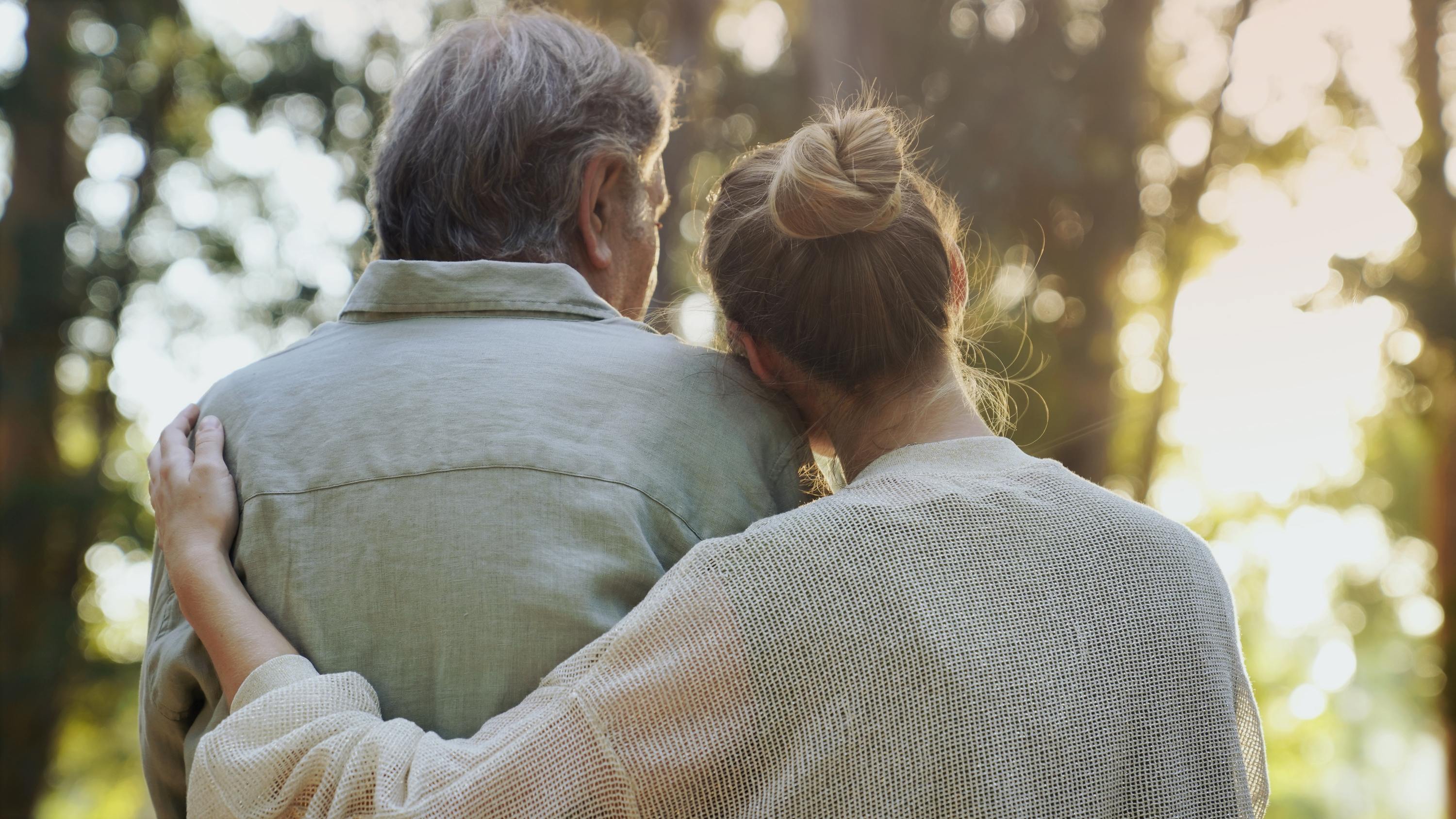 Elderly couple embracing outdoors during golden hour sunset