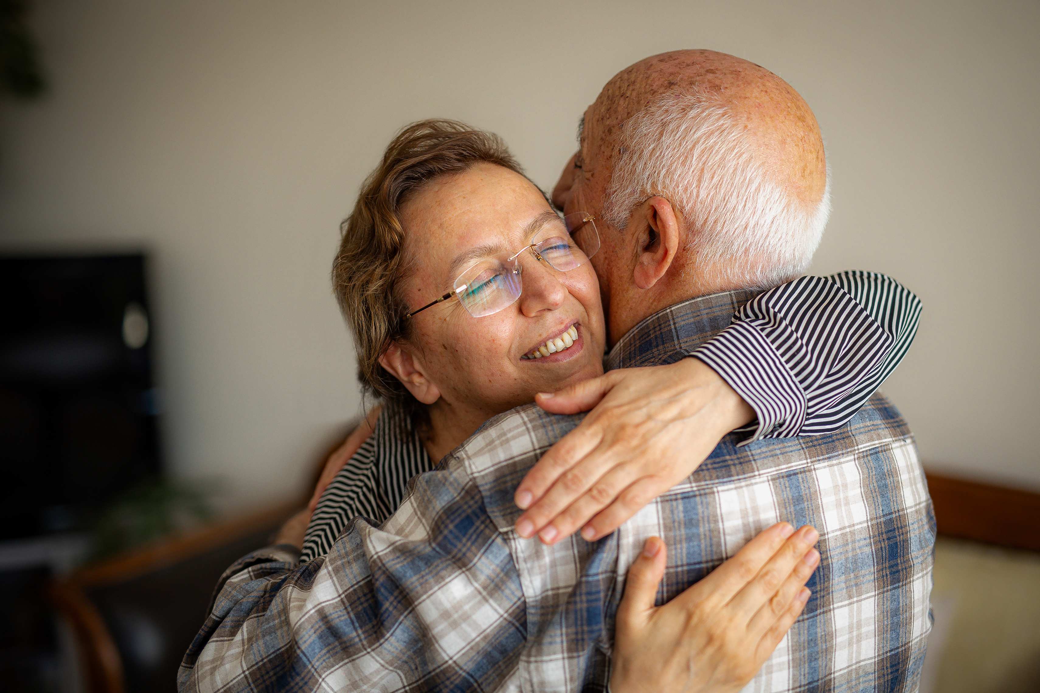 Elderly couple embracing warmly with woman smiling during tender moment
