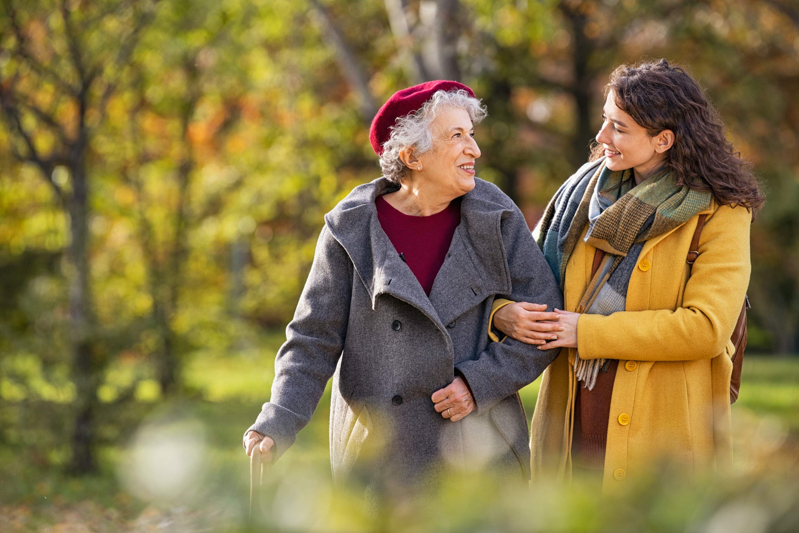 Elderly woman and younger woman walking together in autumn park