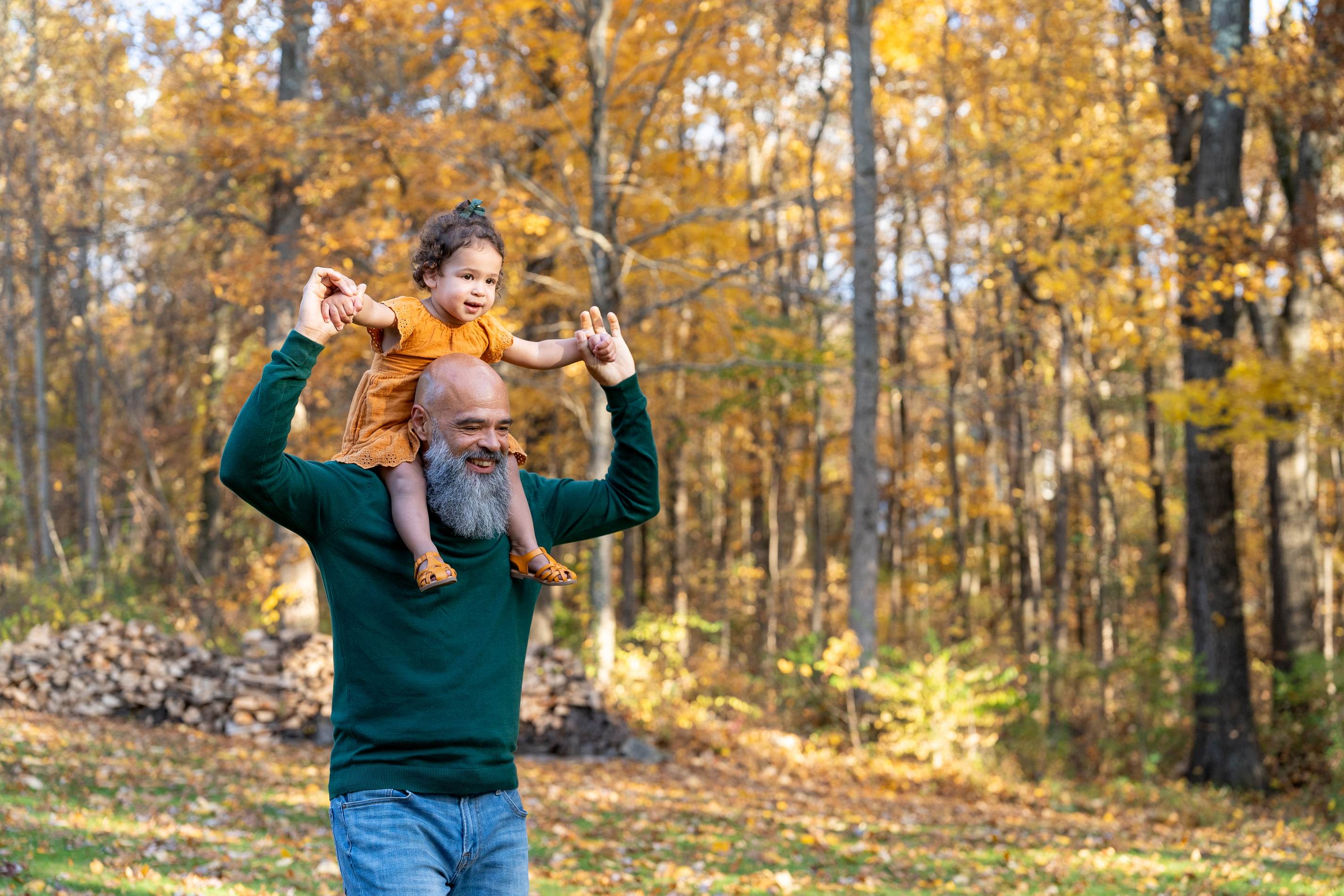 Father carrying young daughter on shoulders in autumn forest