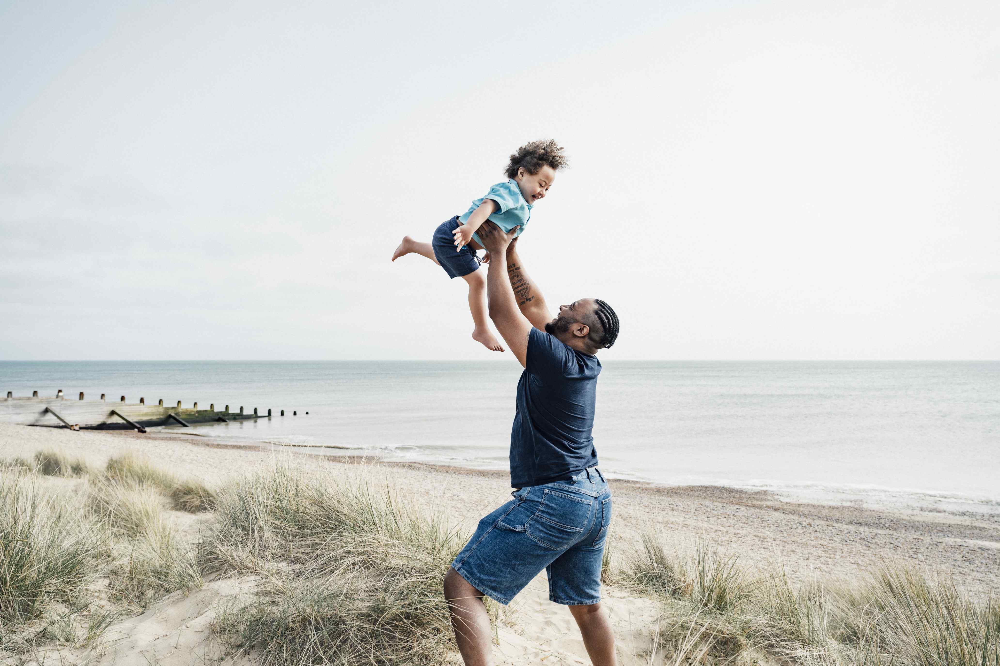 Father lifting young son in the air at beach
