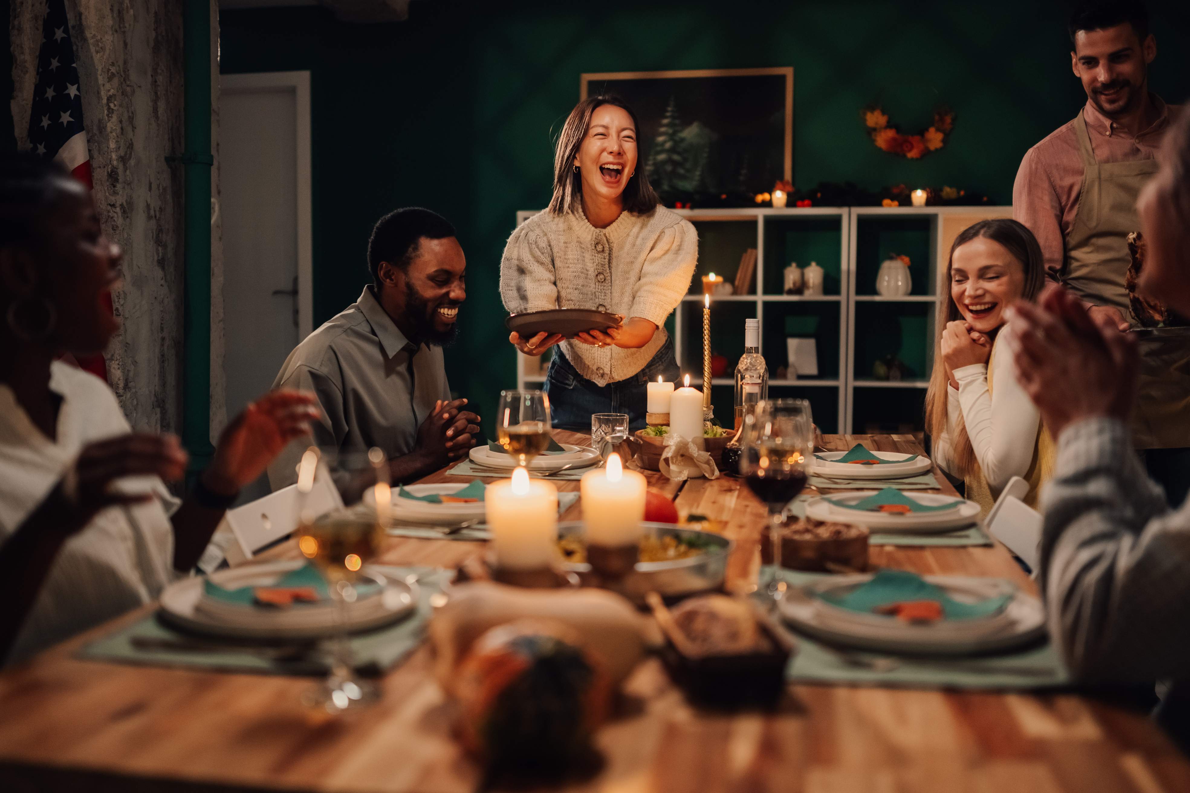 Friends laughing at dinner party with candles and festive table setting