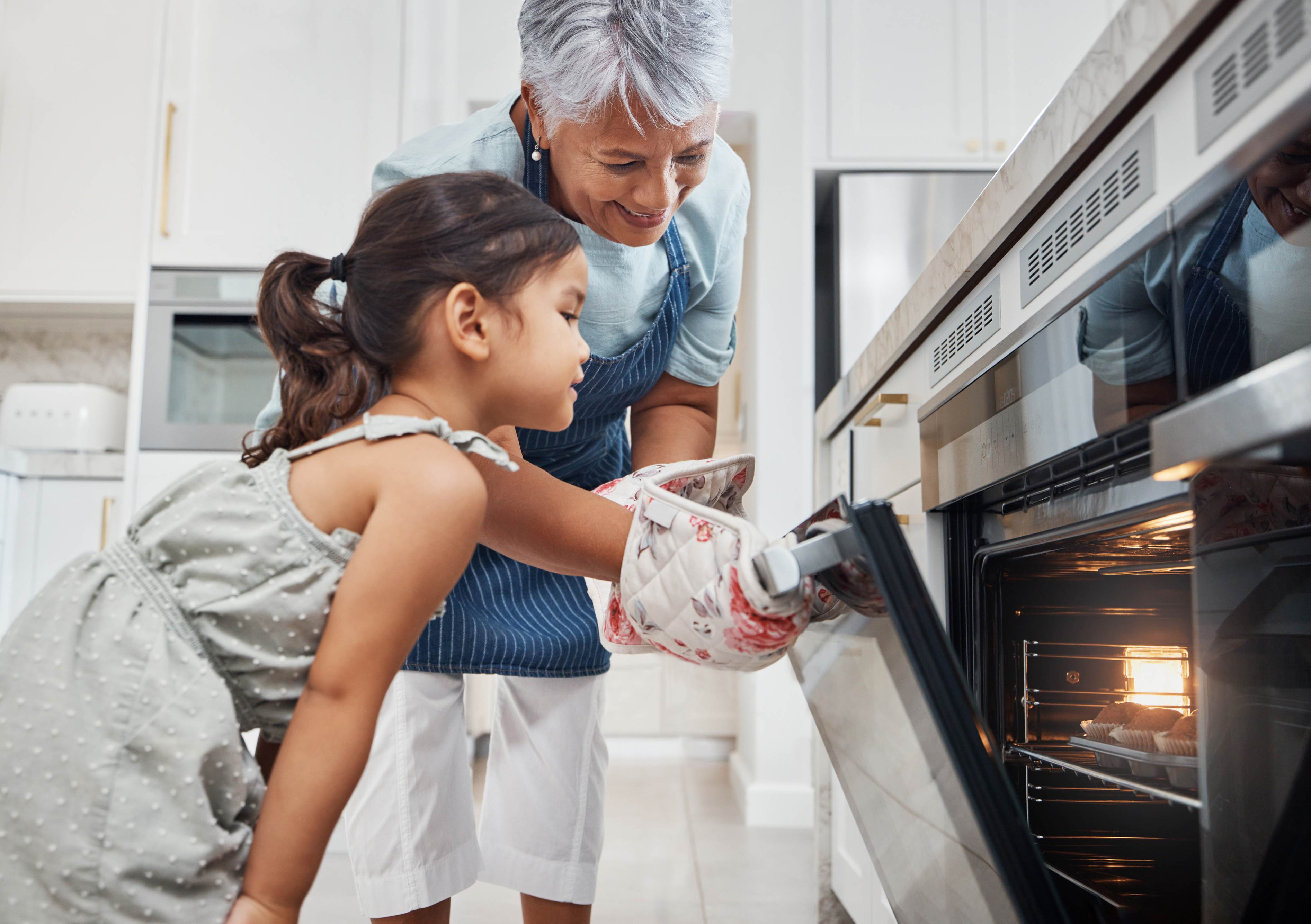 Grandmother and granddaughter baking together in modern kitchen