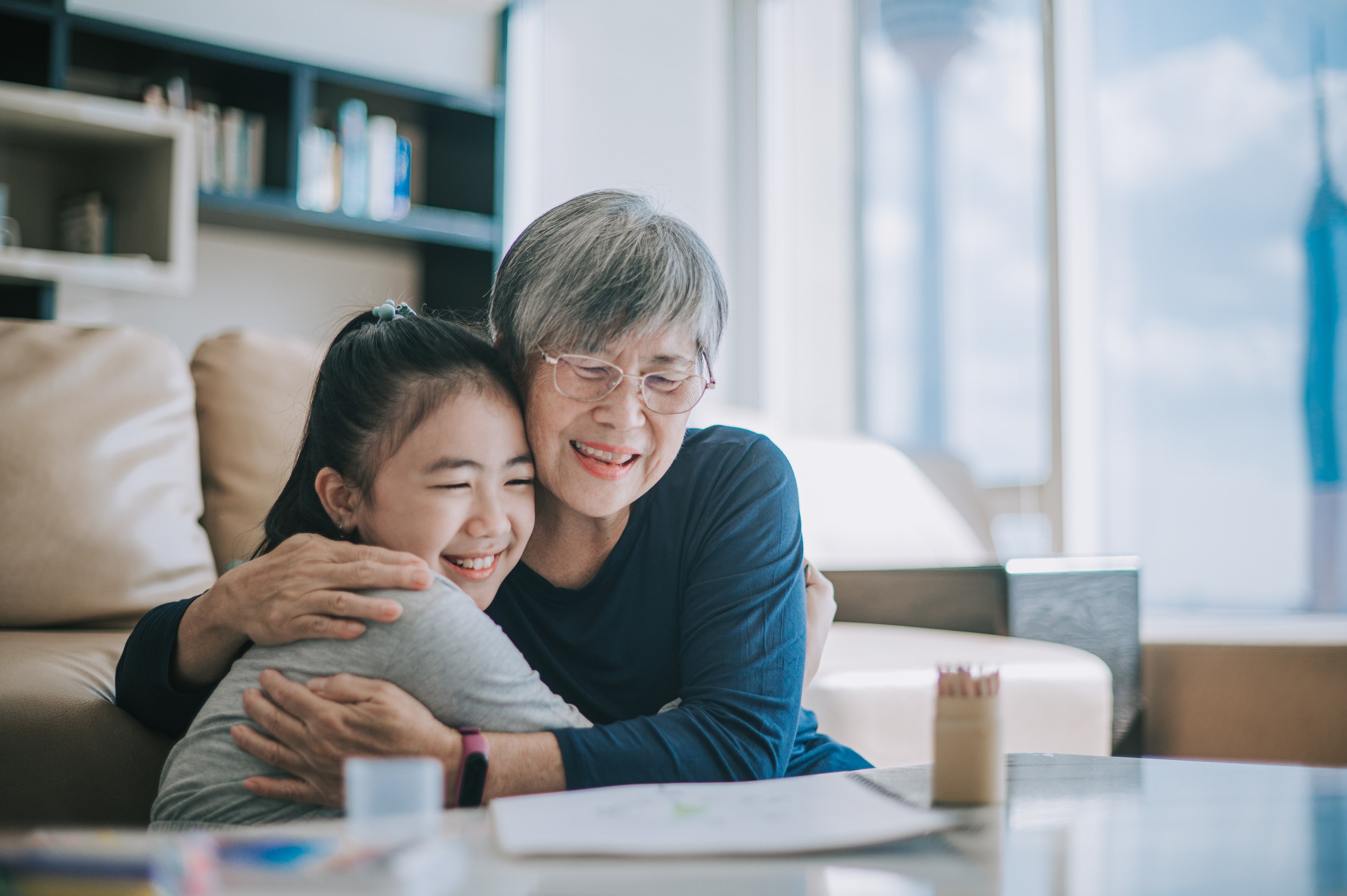 Grandmother and granddaughter hugging warmly at home table