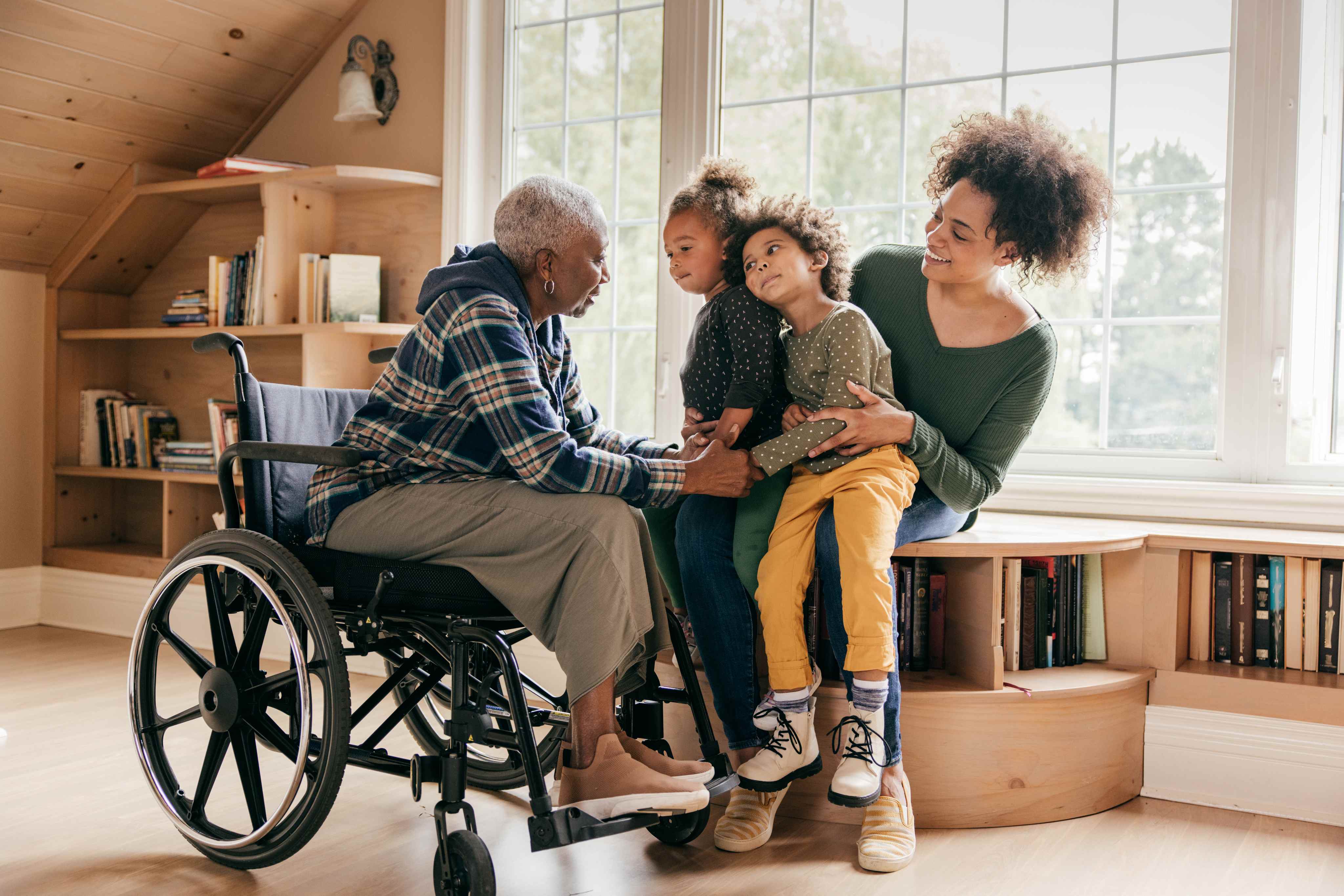 Grandmother in wheelchair with daughter and two grandchildren in cozy room