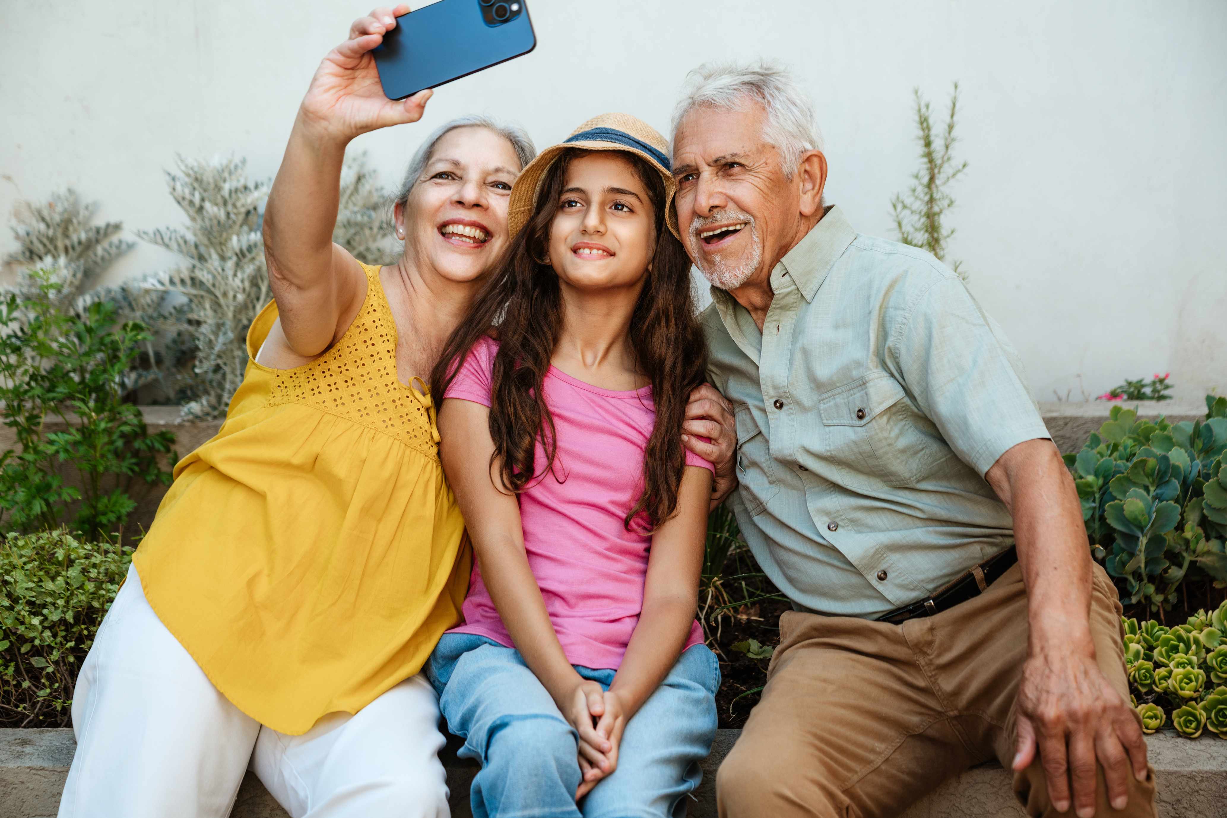 Grandparents and granddaughter taking a selfie together outdoors