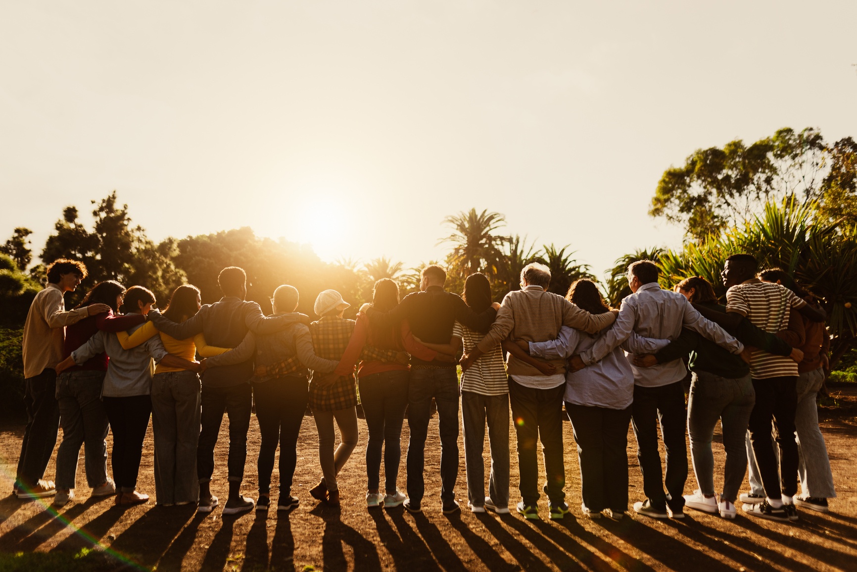 Group of people embracing in unity during golden hour sunset