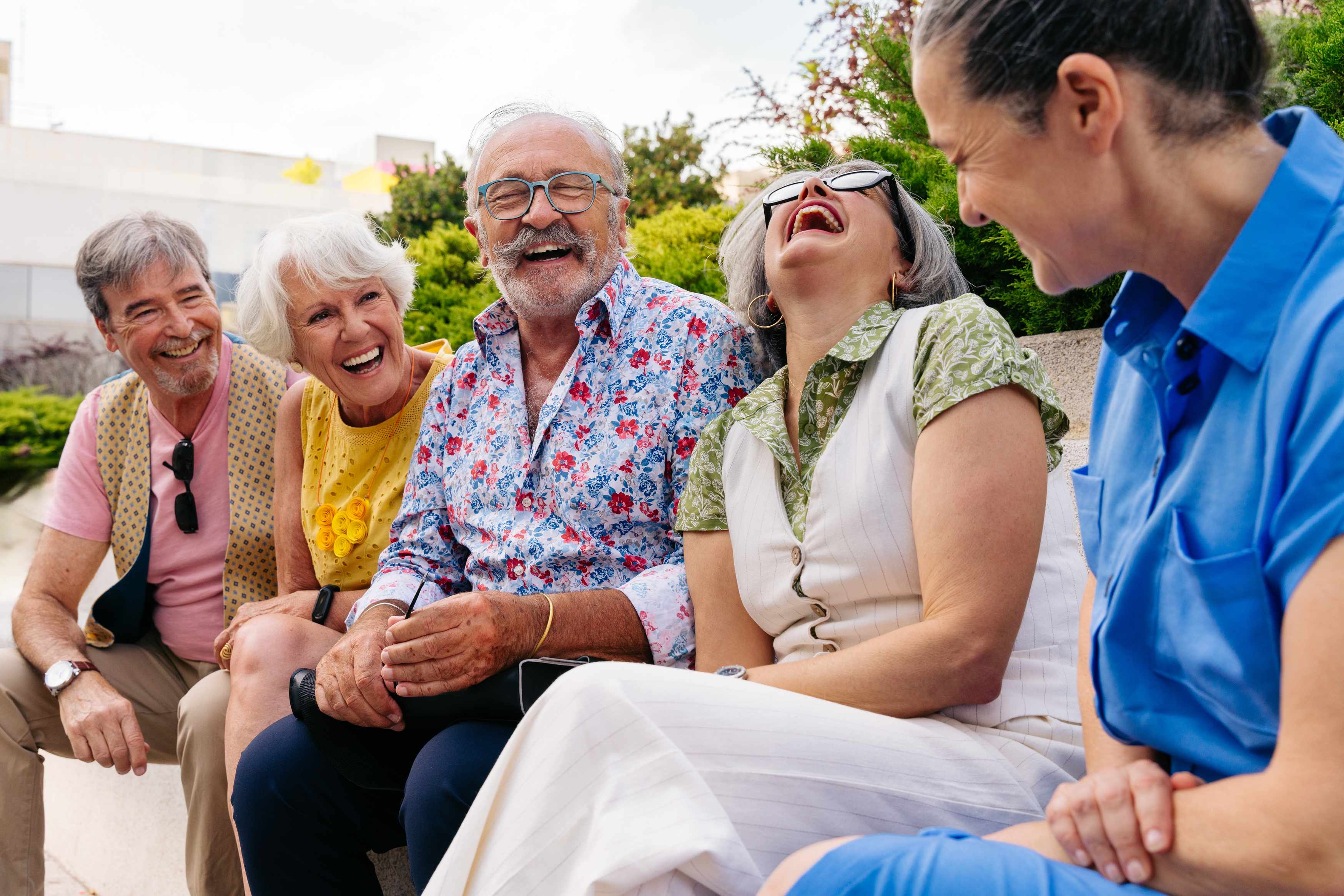 Group of senior friends laughing together outdoors on sunny day