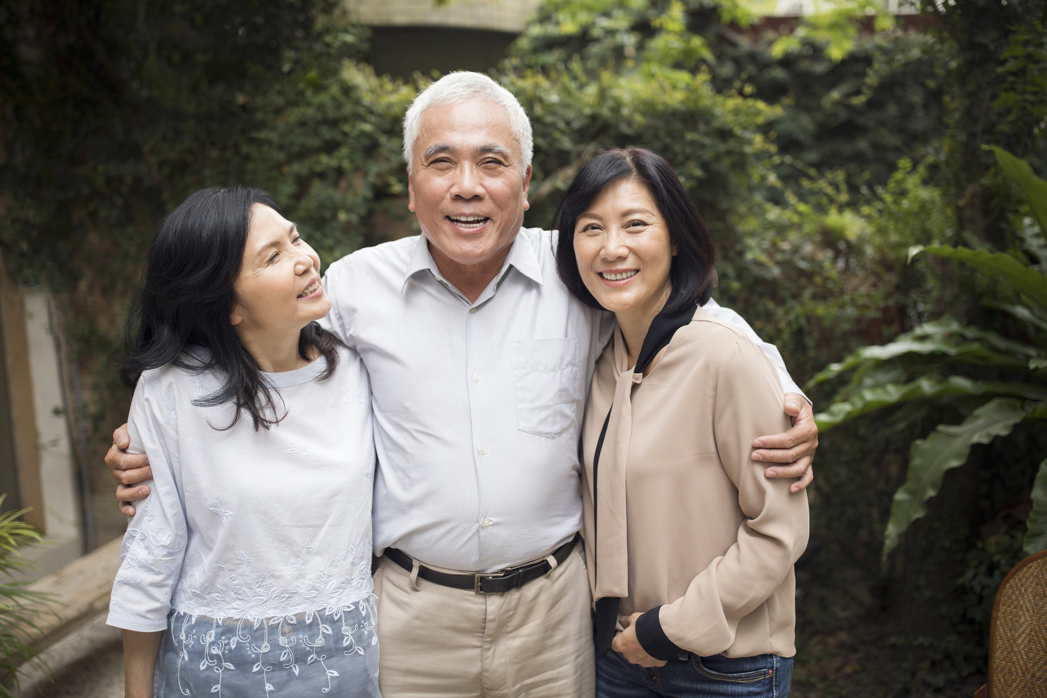 Happy Asian family of three smiling together outdoors