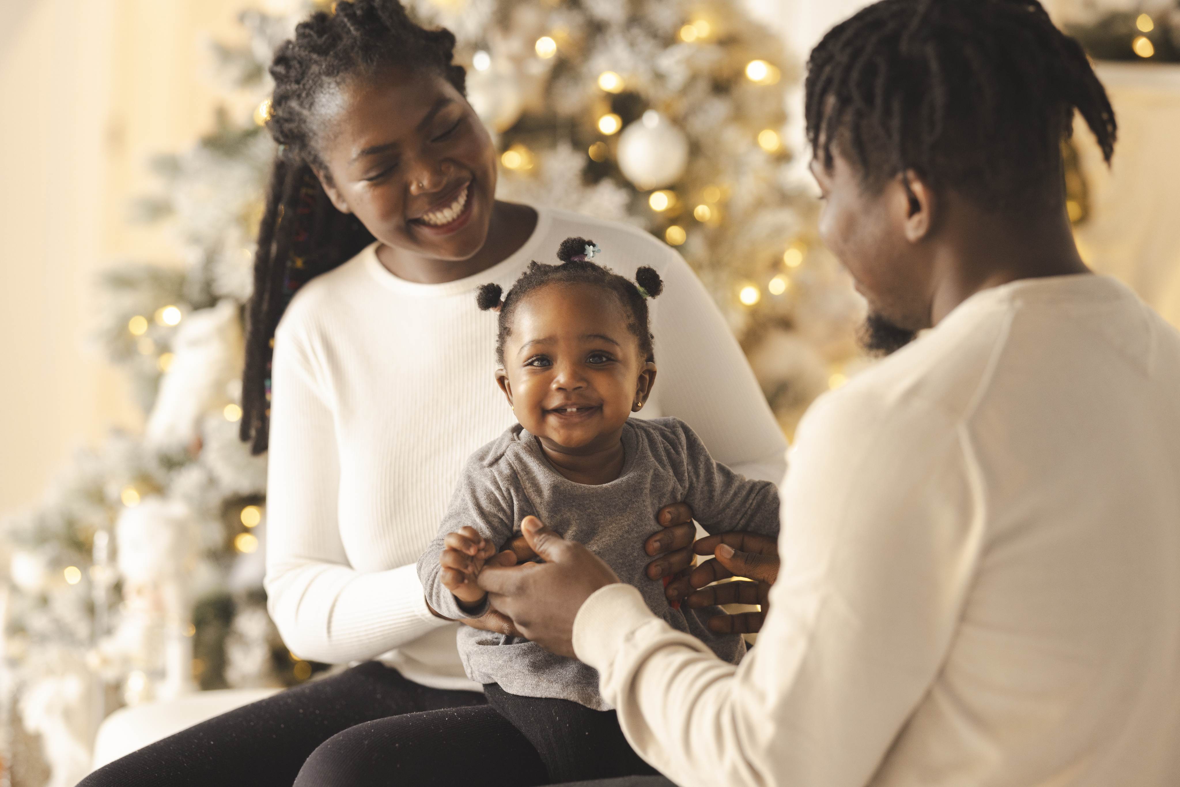 Happy Black family celebrating Christmas together by decorated tree