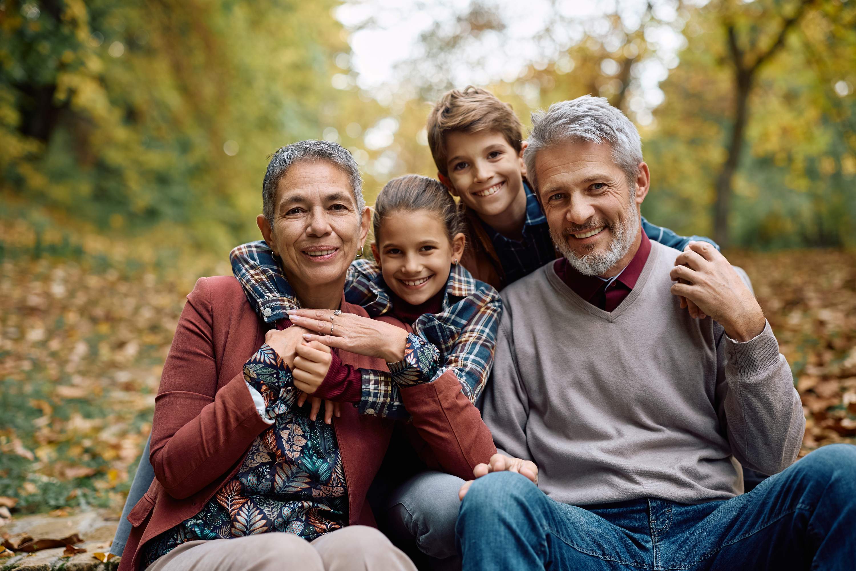 Happy family of four smiling together in autumn park
