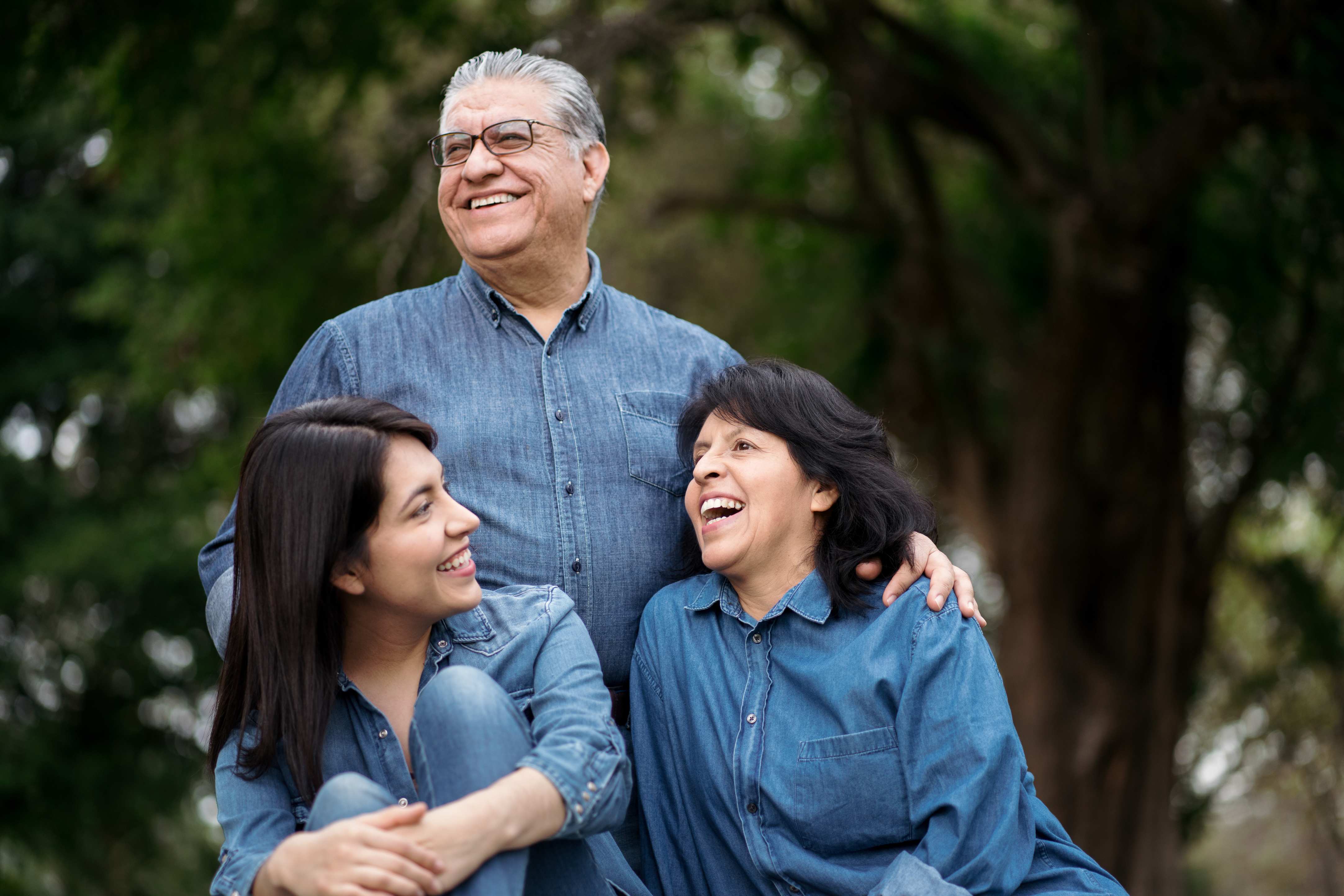 Happy family of three wearing matching denim shirts outdoors