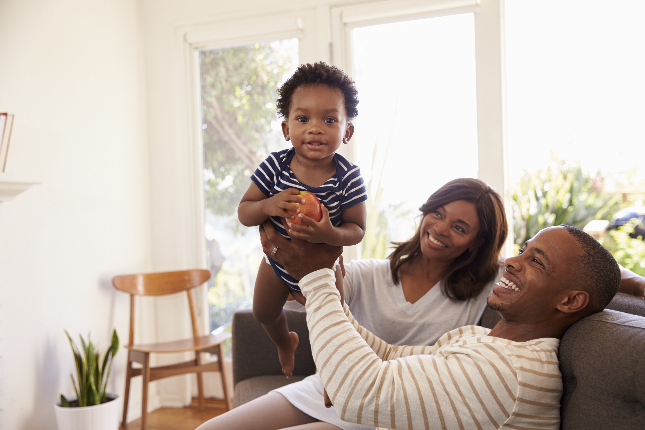 Happy family with young child holding apple in bright living room