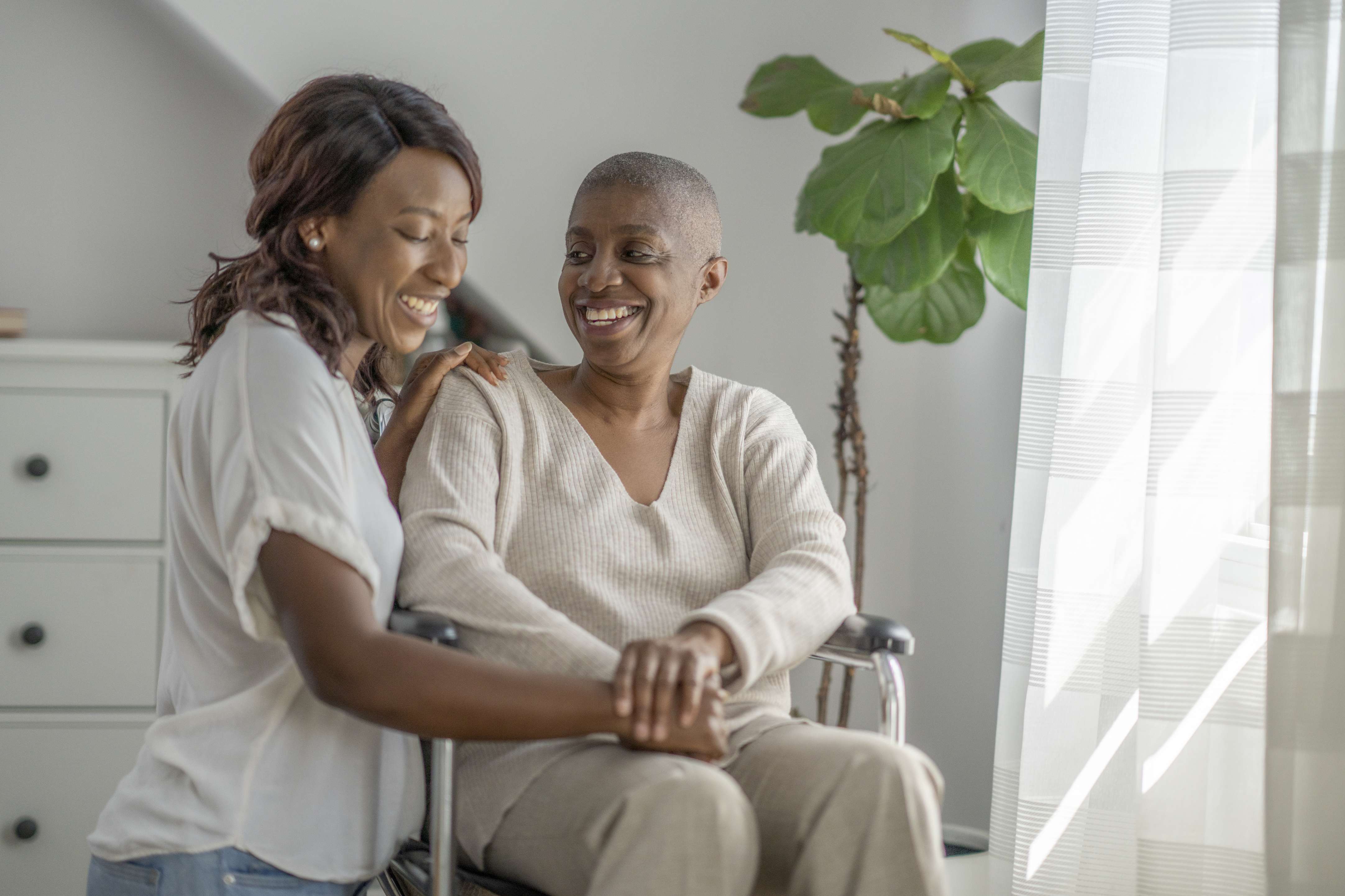 Healthcare worker comforting smiling patient using walker in bright room