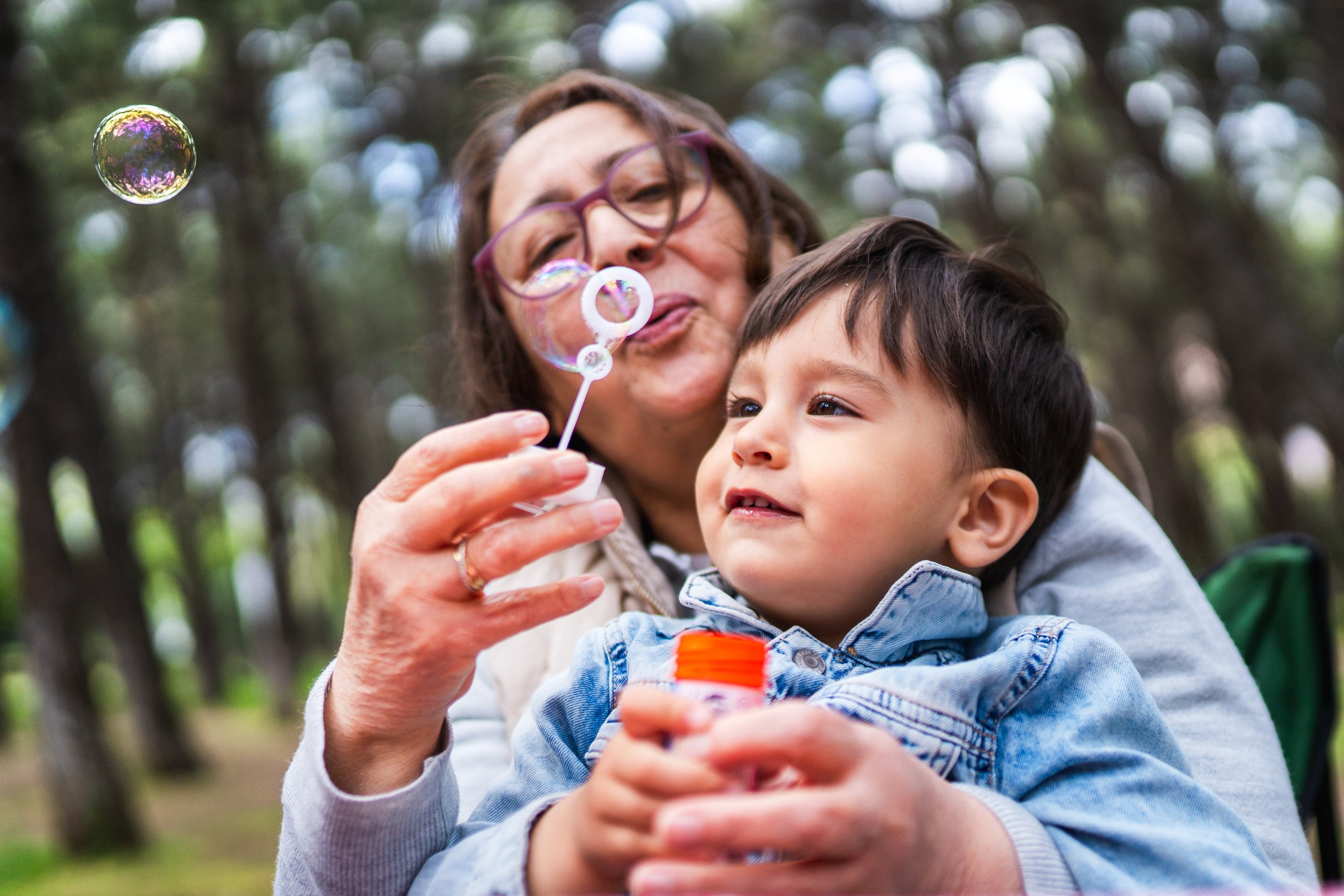 Mother and child blowing bubbles together outdoors