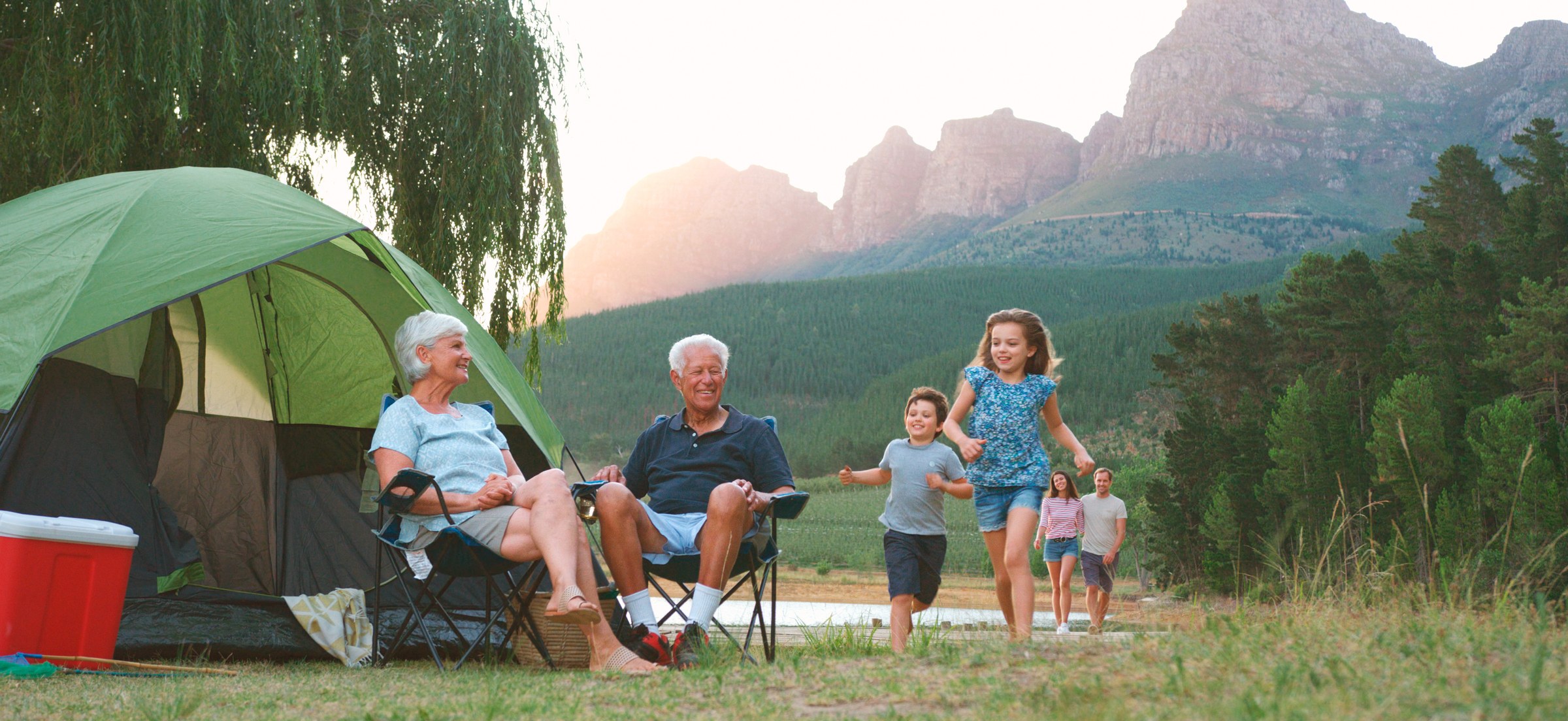 Multi-generational family camping with grandparents and children by mountain landscape