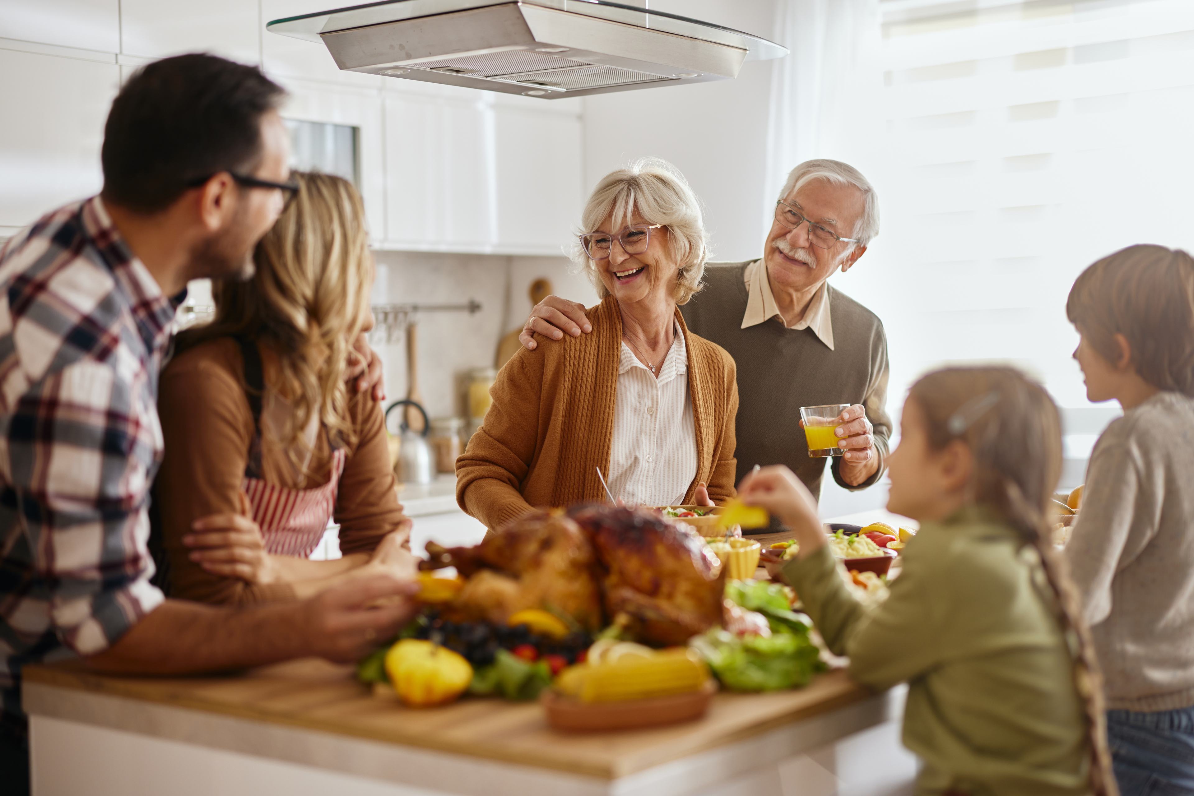 Multi-generational family gathering in kitchen enjoying meal together