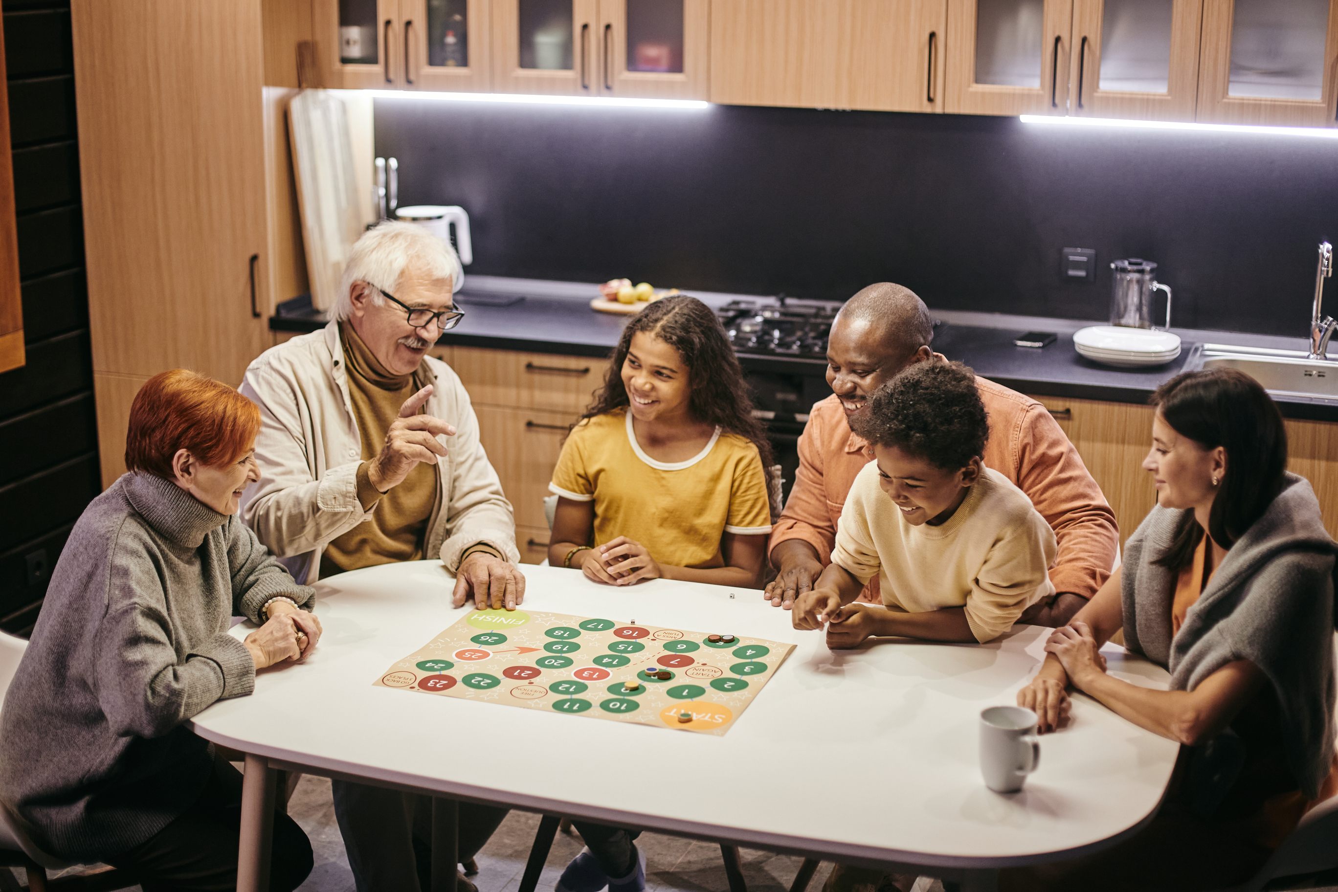 Multi-generational family playing board game together in modern kitchen