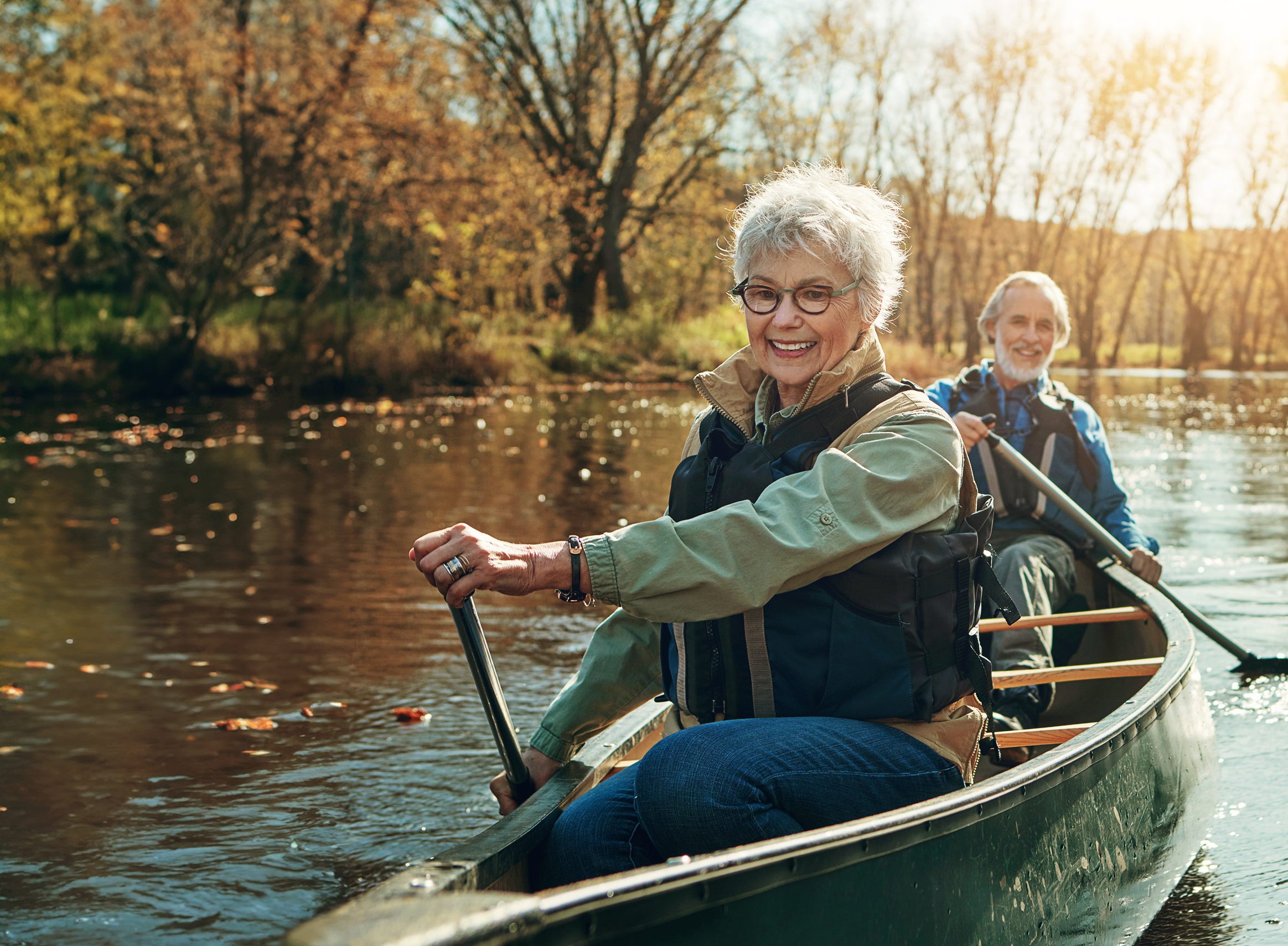 Senior couple enjoying autumn canoe ride on peaceful river