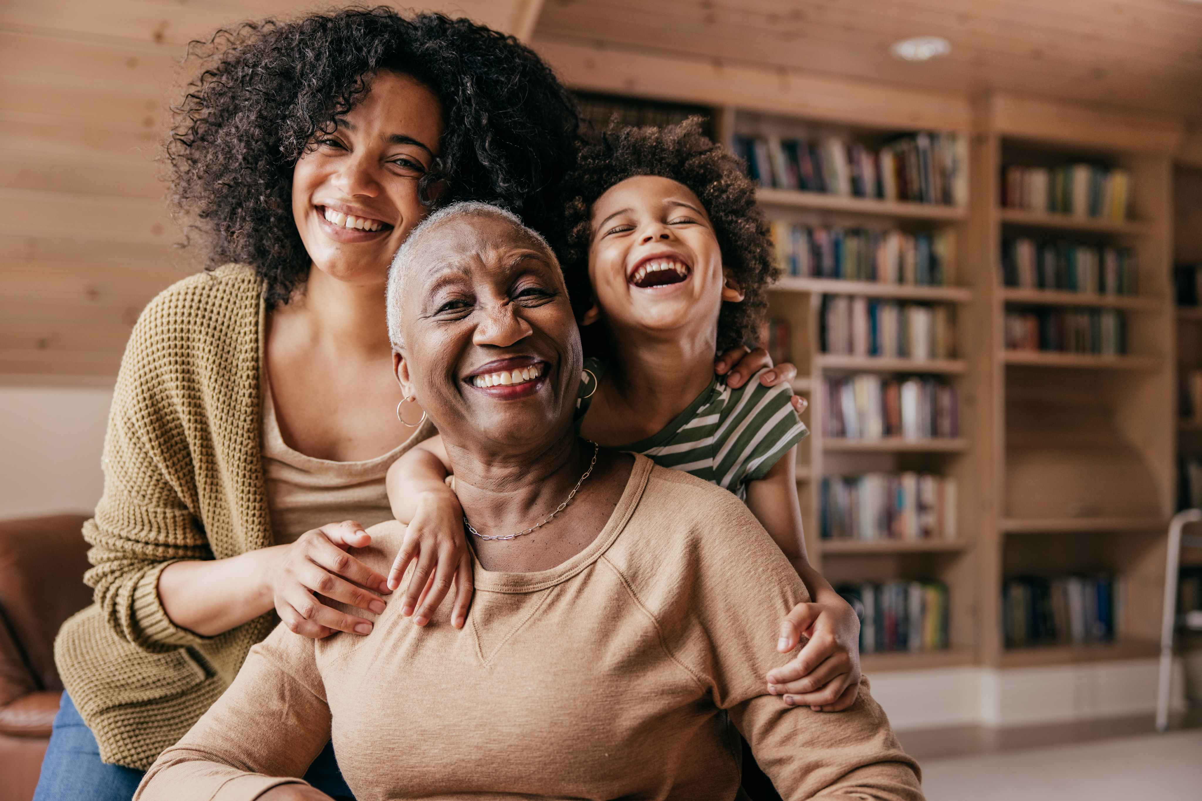 Three generations of women smiling together in home library