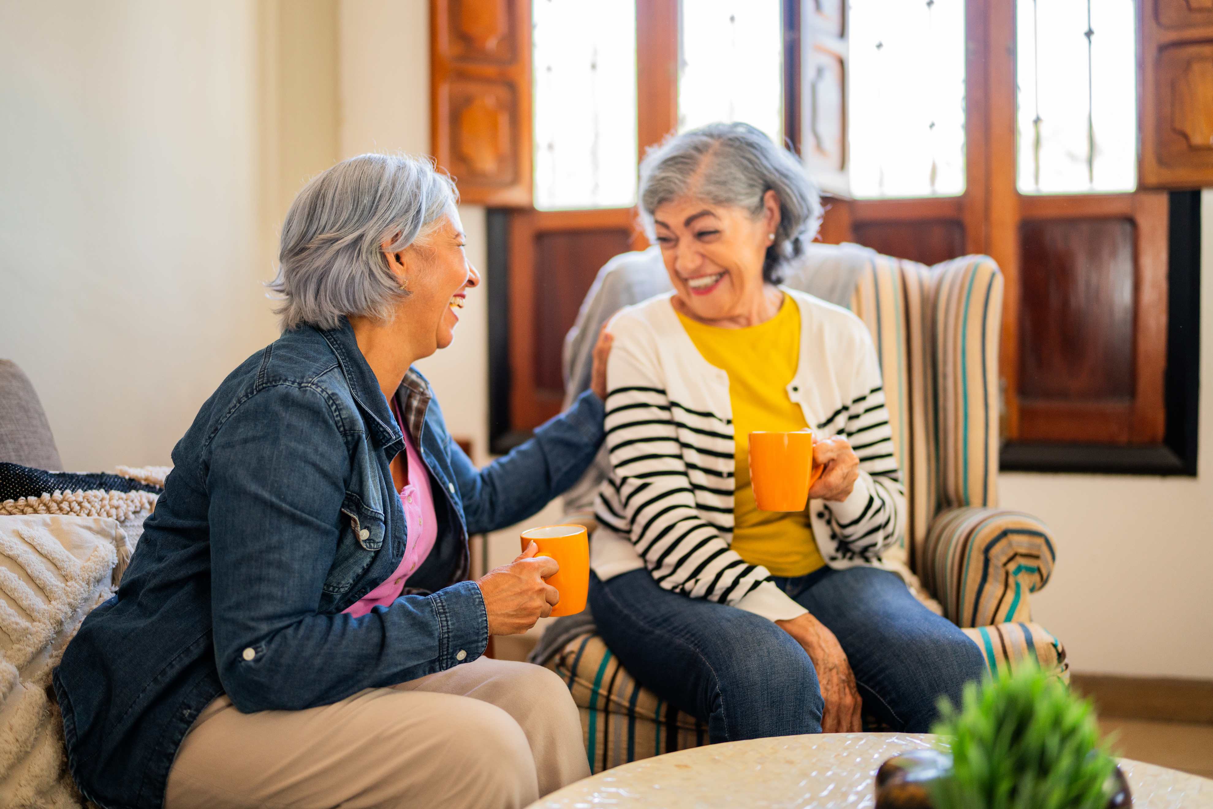 Two senior women enjoying coffee and conversation together at home