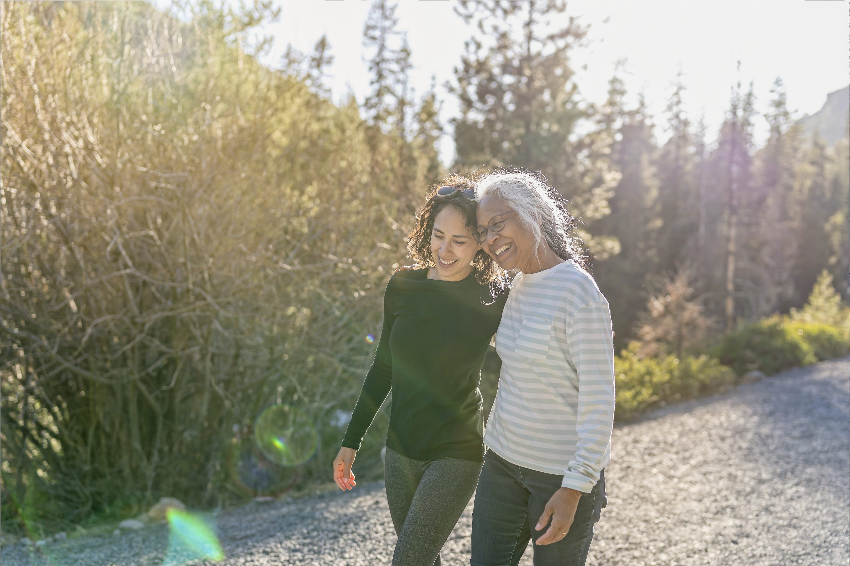 Two women smiling together on sunny nature trail