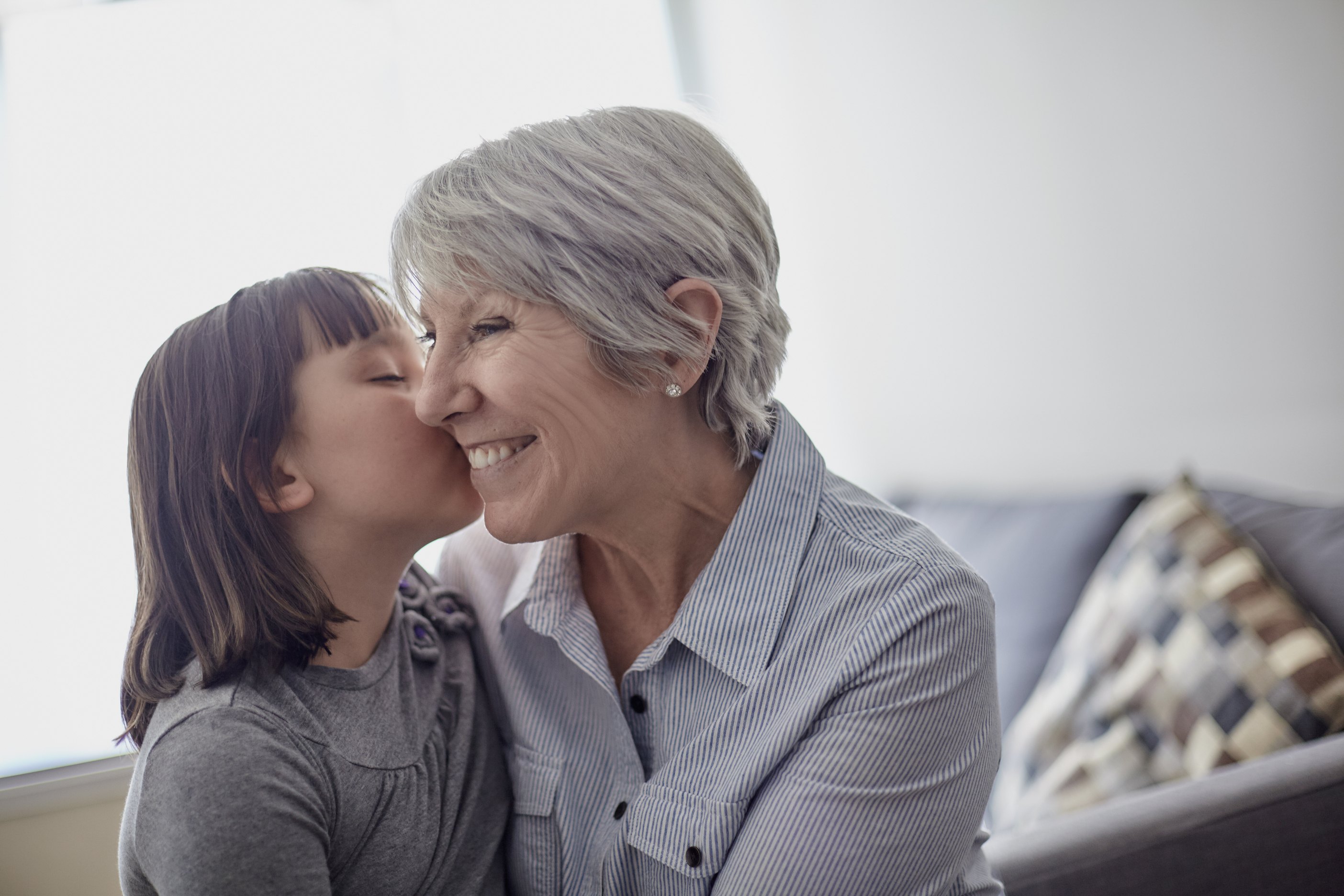 Young girl kissing grandmother's cheek in bright home setting